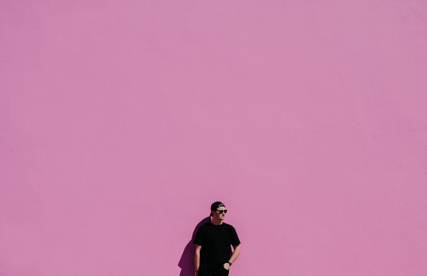 Kille står mot rosa vägg