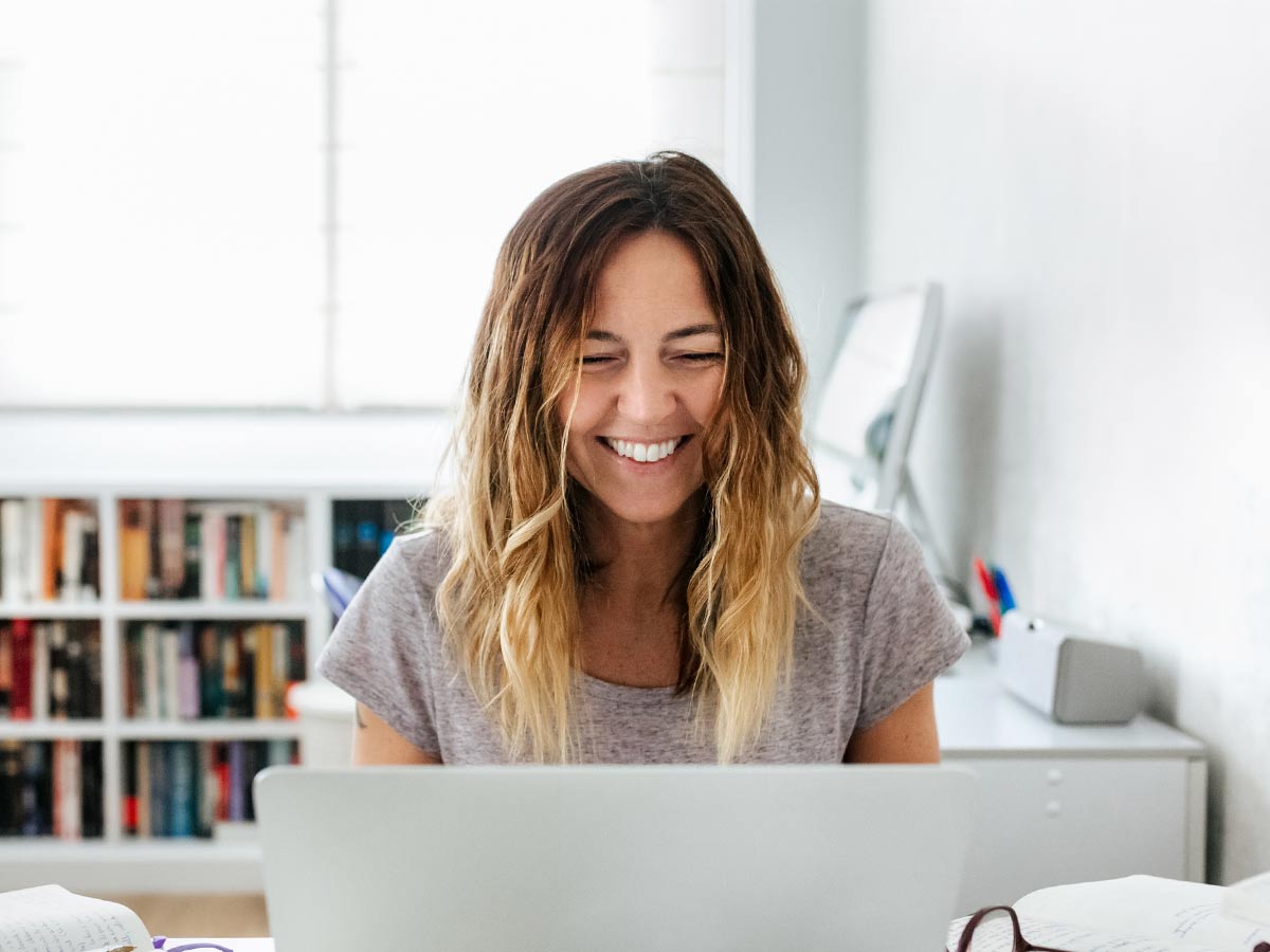 Kvinna ler framför dator