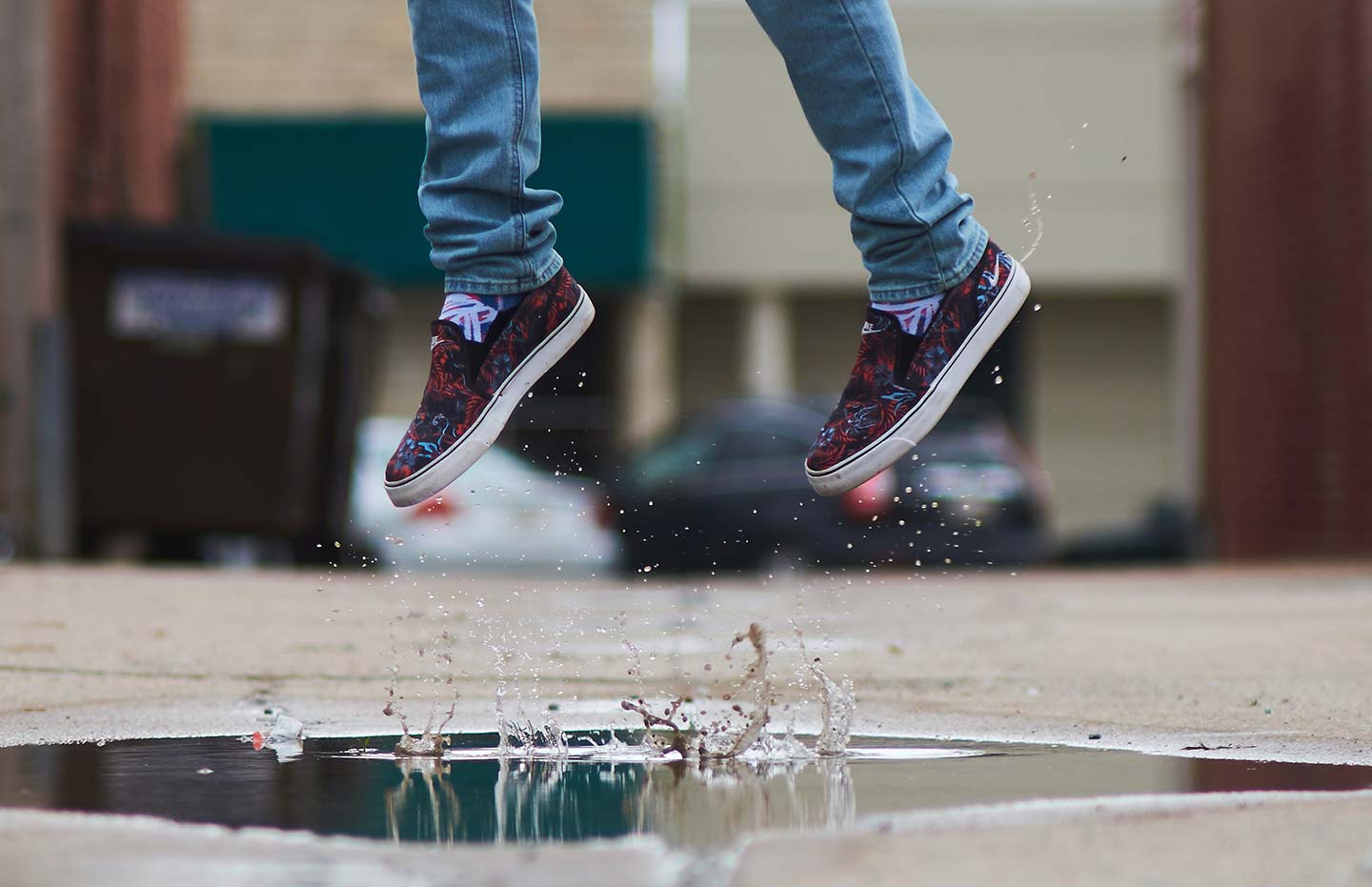 Person i sneakers hoppar i vattenpöl