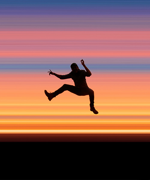 Person hoppar mot färgglad bakgrund.